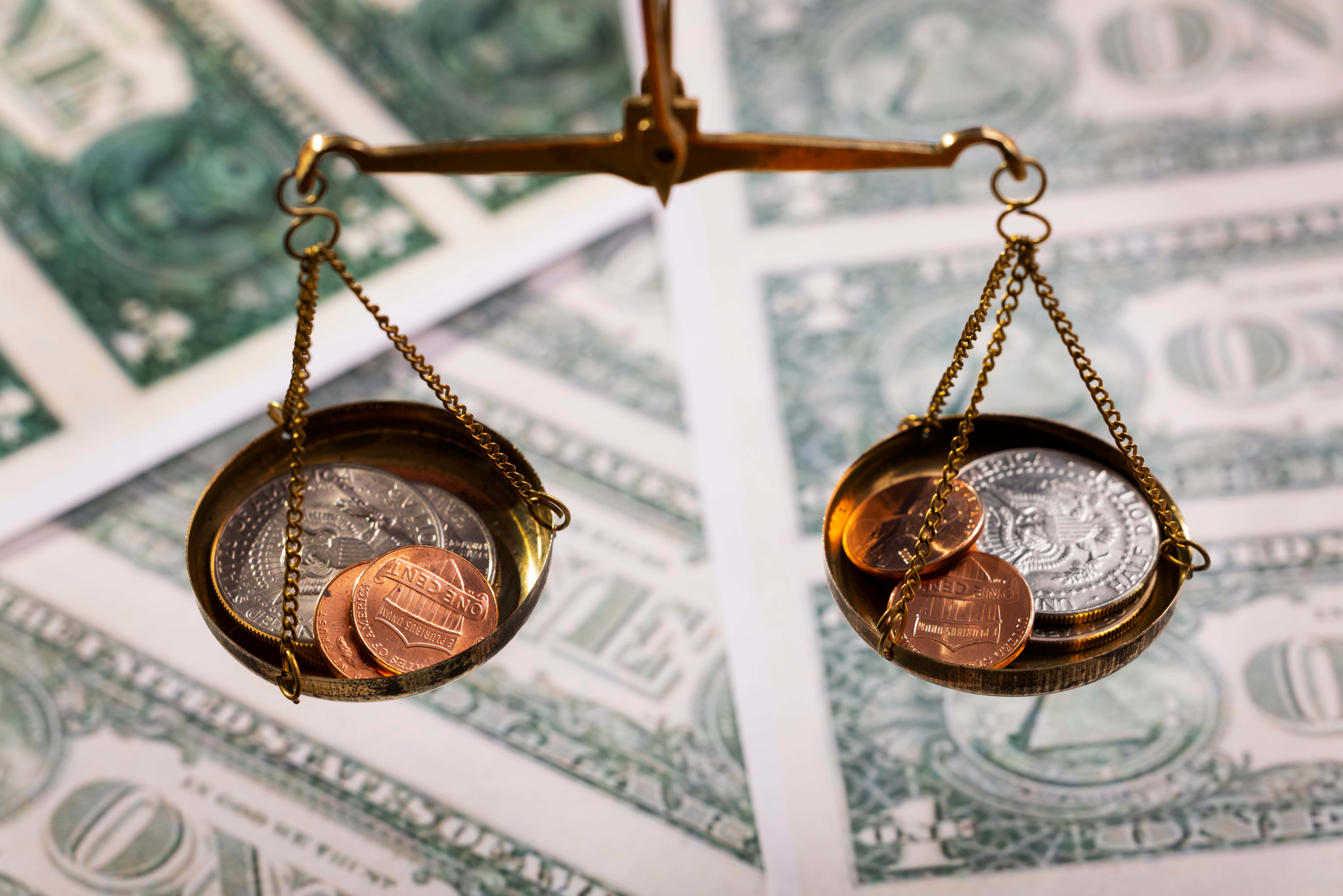 Uma balança jurídica com moedas de ouro sobre notas de dólar - Jerone Toledo Holding