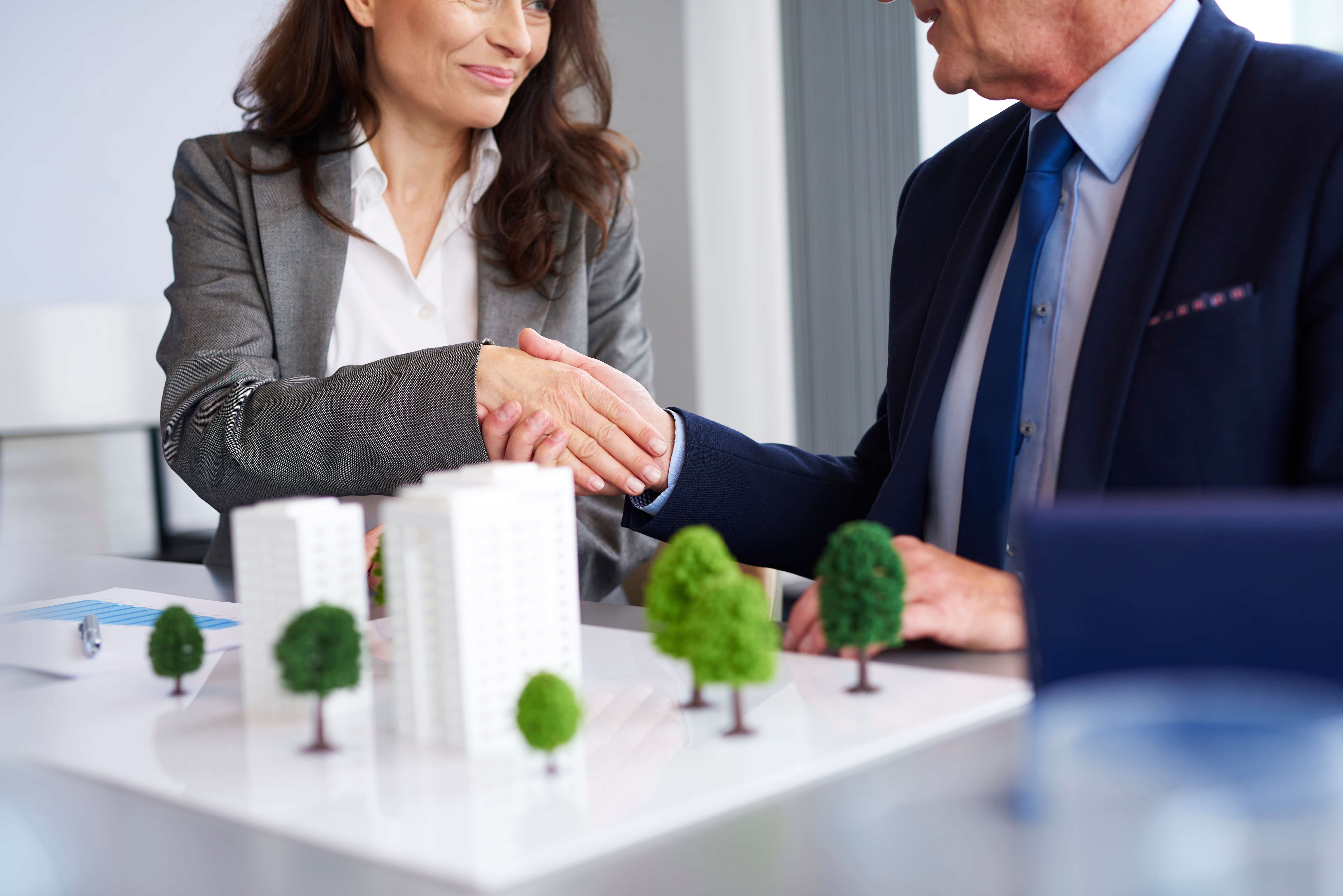 A well-dressed man and woman in a corporate setting closing a deal. - Jerone Toledo Frente